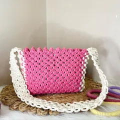 A vibrant pink shoulder bag framed with an off-white border and strap. The scalloped top edge adds a lovely, delicate detail to this eye-catching piece.