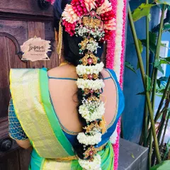 An intricate traditional South Indian bridal hairstyle. This classic braid is heavily adorned with fresh flowers and traditional 'jade billai' hair ornaments, creating a truly regal look for the main wedding ceremony.