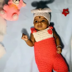 A two-tone romper in red and white, as seen on a happy little client. This style is similar to overalls and is a playful and cute option for a baby's wardrobe.