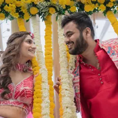 A candid close-up of the couple sharing a laugh between garlands of marigolds at their Haldi ceremony.