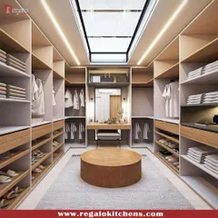 Natural light from a skylight illuminates this U-shaped walk-in closet. We designed it with a central ottoman and a built-in vanity nook, creating a bright and spacious dressing area.