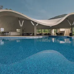The same Aqua Pool & Spa project seen in daylight, where its sweeping, fluid form and parametric ferrocement roof are fully visible. The design captures panoramic views of the Nandi Hills, creating a seamless connection between the built environment and the vast outdoors.