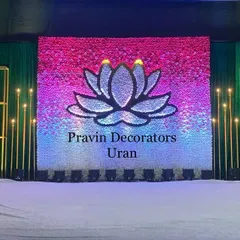 An LED screen can be a great focal point. This engagement stage features a large screen displaying a lotus graphic, flanked by elegant gold candle-wall panels and chandeliers, creating a vibrant and modern look.