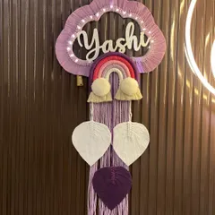 This 'Yashi' nameplate is designed in a lovely lilac and purple color palette. The cloud is illuminated with soft LED lights, and the hanging macrame leaves in white and deep purple create a beautiful, dreamy effect.