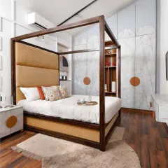 A modern take on a classic, this four-poster bed features a tall, upholstered headboard in a warm ochre fabric. Paired with custom marble-effect nightstands, the design creates a bedroom that feels both grand and deeply comfortable.