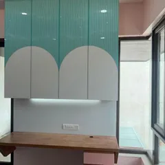 A custom-built study unit for a kids' room. The overhead cabinets in a playful two-tone design provide ample storage for books and supplies, keeping the desk clear.