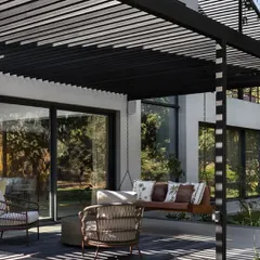 Another view of the outdoor lounge area, highlighting the interplay of light and shadow created by the overhead structure. This space serves as a natural extension of the home's interior living areas.