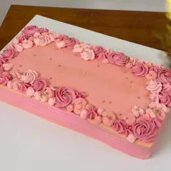 A beautiful rectangular cake in shades of pink, adorned with a cascade of delicate, hand-piped buttercream flowers. This red velvet cake was designed to be a showstopper.