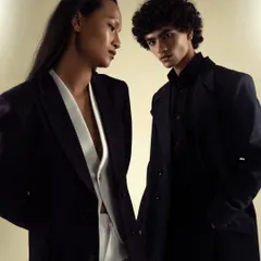 A powerful duo shot for a power-suiting brand. The image showcases both men's and women's tailoring, creating a modern, androgynous, and sophisticated mood.