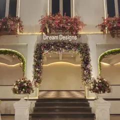 A symmetrical and elegant entrance setup. The central floral arch is flanked by two smaller arches and large floral urns, creating a balanced and picture-perfect welcome.
