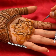 A close-up of me in action, drawing a lotus with one of my fresh henna cones. Every design starts with a single, careful stroke.