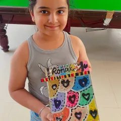 A proud artist with her colorful, heart-filled creation for her dad, Ronak.