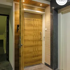 This main door design uses simple vertical grooves and a sleek handle for a modern and minimalist look. The overhead lighting highlights the wooden texture.