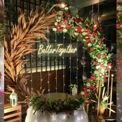 For a modern and stylish anniversary or engagement party, I designed this rustic-chic arch. It combines dried pampas grass with fresh red and white flowers, fairy lights, and a "Better Together" neon sign for a warm, inviting photo backdrop.