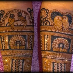 A close up of the fresh henna paste, showing the details of lovebirds and a bride figure before the design is complete.