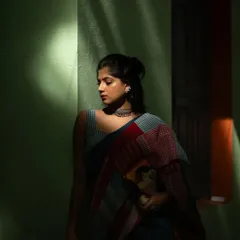 A dramatic shot playing with light and shadow. The contemporary patchwork saree, paired with a modern blouse and clutch, creates a mysterious and artistic portrait.
