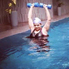 A member performs a shoulder press with aquatic dumbbells. This is a great example of how we build functional strength in a supportive, buoyant environment.