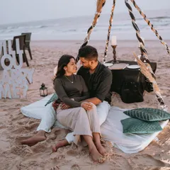 A romantic beach picnic setup for a pre-wedding shoot, complete with a "Will You Marry Me?" sign, capturing the quiet intimacy before the big day.