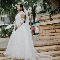 A full-length shot of the bride in her beautiful white wedding gown with a long, elegant train, posing on the steps.