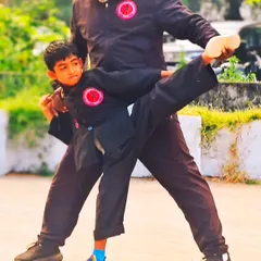 Guiding a young student in a supported side kick. Personal attention is key to helping children learn complex movements safely and correctly.