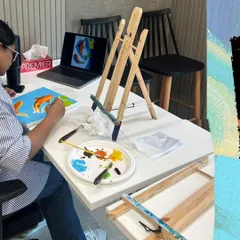 Here's a participant at a corporate workshop, referencing a design on her laptop to create her own koi fish painting. I can tailor the art theme to fit your company's goals or event.