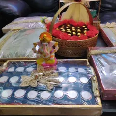 Here is a complete sagan and trousseau display I put together. It includes a tray of silver coins with a Ganesha idol, a basket of chocolates, and beautifully wrapped outfits, creating a cohesive and impressive presentation for the ceremony.