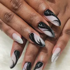 Abstract art for your fingertips. This long, stiletto set features a mesmerizing black and silver glitter swirl design on a sheer base, creating a dynamic and artistic statement.