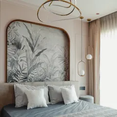 Soft pastels and botanical themes create a dreamy escape in this bedroom. The focal point is a custom arched headboard frame showcasing a beautiful grayscale palm wallpaper. The design is complemented by modern pendant lights, adding a touch of contemporary glamour.