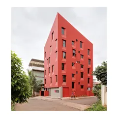 The completed student housing building occupies a corner in a dense residential suburb, redefining its surroundings with its bold form and color.