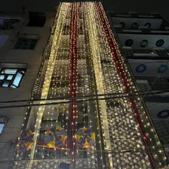 This is how I turn a building into a 'shadi wala ghar'. The entire facade is draped in red and white fabric with vertical streams of fairy lights, creating a grand and festive announcement of the wedding celebrations within.