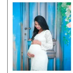 A beautiful and simple solo portrait. The mom-to-be is wearing a lovely white lace dress, and the vibrant blue door backdrop adds a wonderful pop of color, creating a fresh and modern feel.