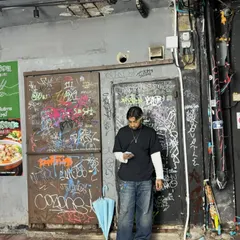 A candid moment checking my phone in front of a graffiti-covered wall. The streets are always a source of inspiration.