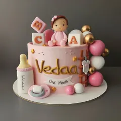 Celebrating one month in this world for baby Vedaa. This pretty pink chocolate truffle cake is adorned with baby essentials like blocks, a pacifier, and a milk bottle.