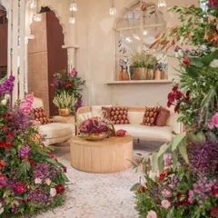 For this "Garden of Vows" wedding, I created an intimate lounge nook surrounded by an abundance of colorful flowers. The plush sofa and modern wooden tables provide a comfortable and beautiful spot for guests to gather.