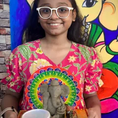 I love seeing the pride on a child's face when they complete their masterpiece. Here, a young artist proudly displays her handmade clay Ganesha idol, sculpted and decorated during our festive workshop. This is a great example of our hands-on clay modeling sessions for kids.