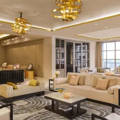 This lounge room in the 'DLH' residence is crafted for vibrant social life and quiet relaxation. Set in neutral tones with elegant gold accents, the space is defined by French windows that invite limitless possibilities. It is a perfect setting for conversations over coffee or cocktails.