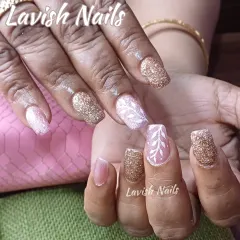 A beautiful mix of rose gold and pink glitter nails with a hand-painted white leaf design on an accent nail, perfect for a sophisticated look.