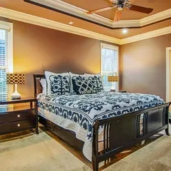 A master bedroom painted in a warm, earthy brown. The paint complements the dark wood furniture and creates a cozy, traditional feel.