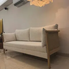 This elegant sofa, made from solid oak with natural cane side panels, brings a light and airy feel to the living room. The neutral fabric and clean lines make it a versatile piece for modern homes.