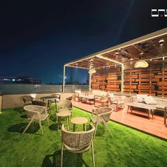 We designed this rooftop lounge to be an urban sanctuary. The space combines natural textures like wood decking and an artificial grass lawn with comfortable, modern outdoor furniture. A slatted wood pergola with integrated LED lighting provides both shade and ambiance, creating the perfect setting for relaxation and social gatherings.