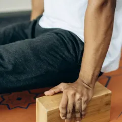 A close-up of a hand gripping a yoga block, ready to support and elevate the practice. Props are an integral part of our teaching methodology.