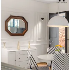 A closer look at the dining area in the Denkanikotta home. The octagonal wooden mirror and classic sideboard complement the modern chairs and pendant light, showing our attention to interior design details.