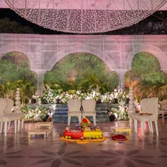The wedding mandap, set against a backdrop of ethereal white arches and a vertical garden. The minimalist seating and clean lines emphasize the grandeur of the sustainable design, where nature and architecture meet.