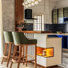 A close-up of a stylish breakfast bar that serves as a divider between the kitchen and living area. The combination of wood, white surfaces, and unique lighting creates an inviting spot for morning coffee or evening chats.