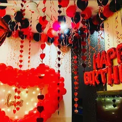 This is an immersive romantic birthday setup in a classic red and black theme. I filled the room with heart garlands, ceiling balloons, and a large heart-shaped balloon frame illuminated with fairy lights for a dramatic effect.