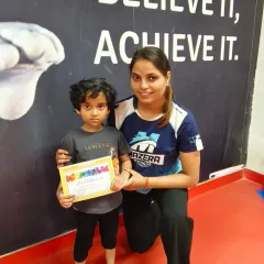A proud moment for one of our young gymnasts, posing with her coach and certificate in front of our motivational wall.