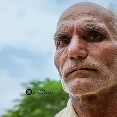 This is another angle from the same street portrait session. The slightly off-center composition and the soft background help to emphasize his weathered features and steady gaze.