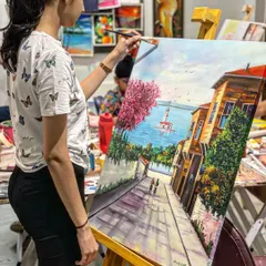 A student works on a detailed cityscape painting in acrylics. We learn about perspective and composition to create scenes that draw the viewer in.