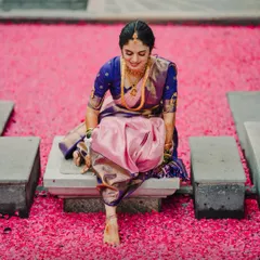 An artistic and unique bridal portrait with the bride seated on a bed of vibrant pink flower petals. This shot is a beautiful blend of tradition and modern artistry.
