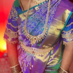 A close-up of the beautiful drape and traditional jewelry. The rich texture of the Kanjeevaram silk is highlighted by the neat pleats and the ornate waistband (vaddanam).